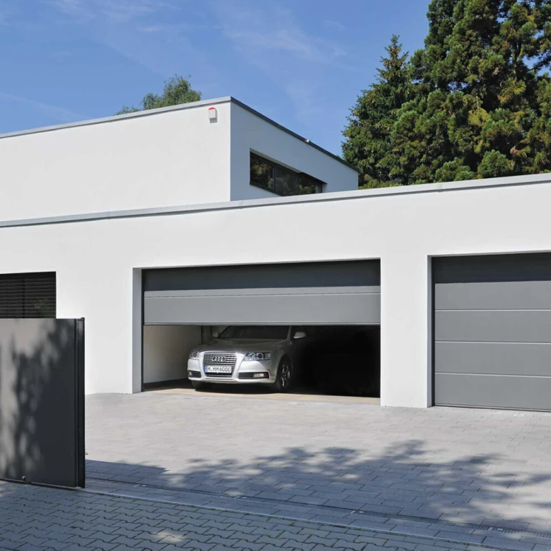 Modernes Einfamilienhaus mit flacher Dachform, Doppelgarage und geöffneter Garagentor.